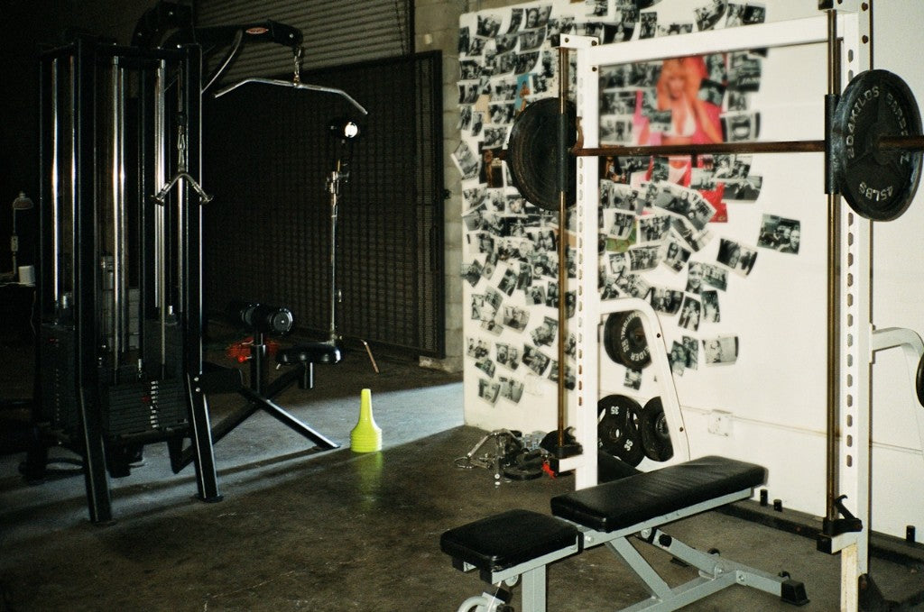 Industrial gym interior with squat rack, cable machine, and photo wall